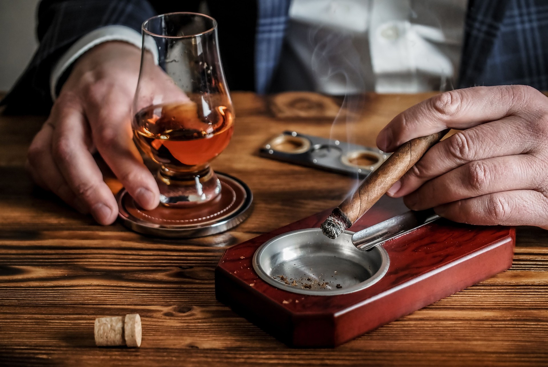 Man at a bar drinks whisky and smokes a cigar